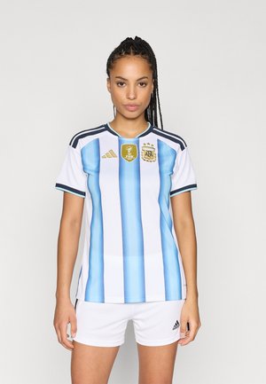 Maillot de football blanc avec des rayures bleu clair, featuring des logos Adidas et d'équipe, associé à un short blanc. Manches courtes et design col rond.