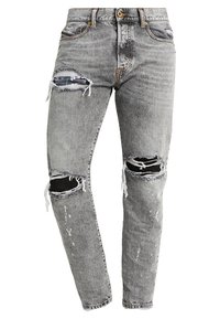 Grå slitna skinny jeans med rivna hål på båda knäna och på överlåren, med fransiga kanter och knappstängning i midjan.
