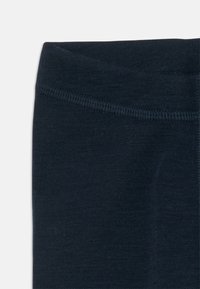 Leggings azul escuro com uma textura suave e macia e uma cintura elástica. Apresenta costura ao longo da cintura e da perna. Sem padrões ou acentos.