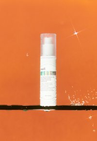 Vit cylindrisk serumflaska med pumpkork, texturerad yta och kondens, uppställd mot en orange bakgrund. 30 ml storlek.