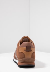 Baskets en daim et cuir marron avec un contrefort de talon texturé, une semelle intermédiaire blanche et des accents contrastants. Dotées d'une languette de tirage à l'arrière.