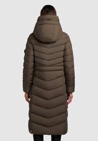 Garšs, olīvzaļš pūkains mētelis ar ševronu rakstu, kapuci un sānu kabatām. Gluda tekstūra un elegants dizains nodrošina siltumu un komfortu.