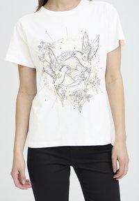 White cotton T-shirt featuring a graphic of two birds facing each other, surrounded by floral and circular designs in gray and gold accents.