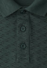 Tummanvihreä poolopaita, jossa on hienovarainen musta abstrakti kuvio ja kolme mustaa nappia, joihin on kaiverrettu "STREET ONE MEN".