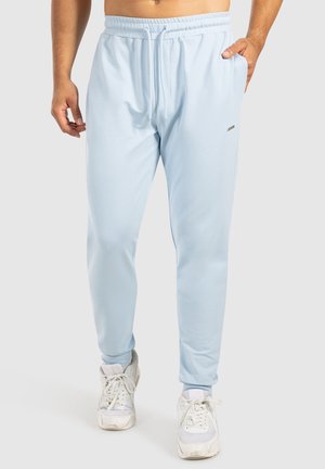 Helle blaue Sporthosen mit elastischem Bund und Kordelzug. Glattes Material, schmaler Schnitt und ein kleines Logosymbol am Bein.