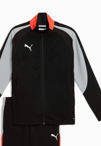 Tuta Puma composta da una giacca con zip nera con dettagli grigi e arancioni, e pantaloni neri abbinati, entrambi realizzati in un materiale leggero.