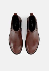 Chaussures en cuir marron à enfiler avec des panneaux élastiques sur les côtés, bouts arrondis et semelles en caoutchouc texturé. Dotées d'une petite languette à l'arrière pour un enfilage facile.