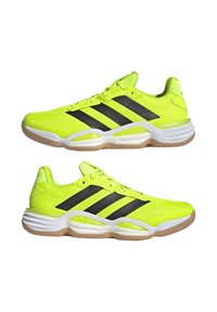 Zapatillas deportivas de color amarillo neón con rayas negras, parte superior de malla, suela de goma y acentos texturizados; cuentan con una media suela acolchada para mayor comodidad.