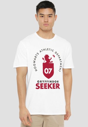 Young man wearing a white T-shirt with "Hogwarts Athletic Department 07 Gryffindor Seeker" and a red lion crest on the front.