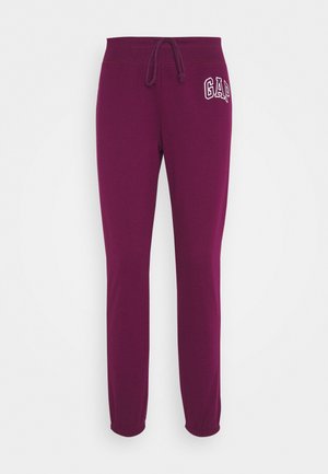 Pantalon de survêtement violet avec des poignets élastiques et une taille à cordon, arborant un logo "GAP" blanc sur la partie supérieure de la cuisse gauche.