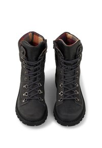 Par af sorte læder vandrestøvler med tykke såler, metaløjer og ternet stoffor, vist oppefra mod en hvid baggrund.