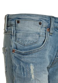 Jeans de mezclilla azul claro con textura desgastada, que cuentan con bolsillos traseros, herrajes de cobre y detalles de costura visibles.