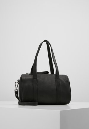 Czarna skórzana torba podróżna z dwoma krótkimi uchwytami i odpinanym paskiem, o gładkiej fakturze i cylindrycznym kształcie. Srebrne akcenty metalowe.