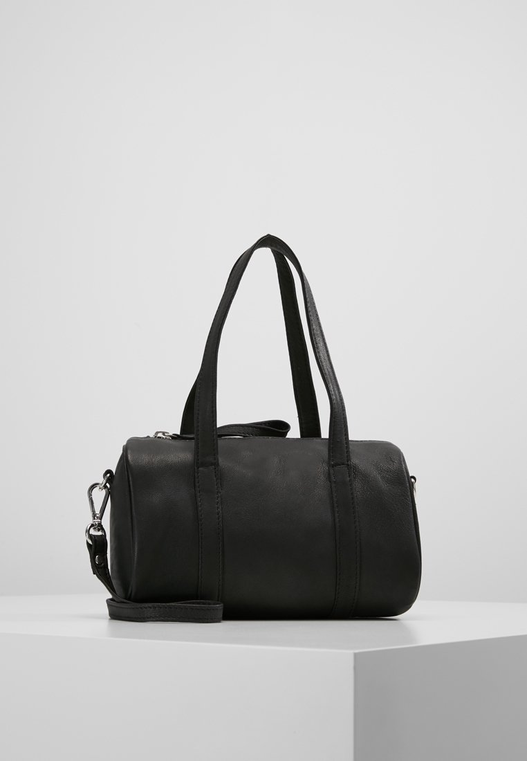 Czarna skórzana torba podróżna z dwoma krótkimi uchwytami i odpinanym paskiem, o gładkiej fakturze i cylindrycznym kształcie. Srebrne akcenty metalowe.