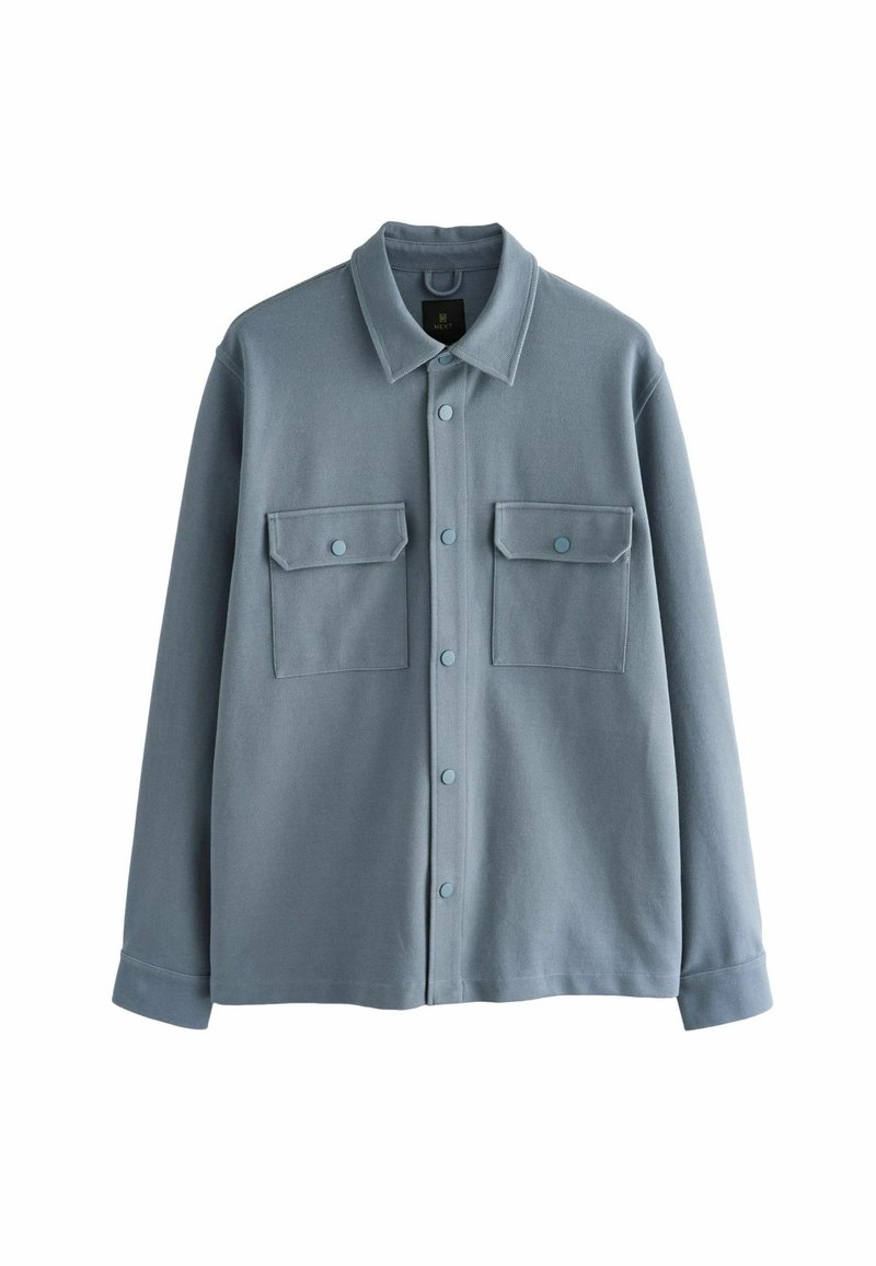 Veste-chemise gris-bleu à manches longues avec col, fermeture à pression et deux poches à rabat à l'avant avec boutons.