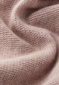 Miękka dzianina w stonowanym różowym kolorze, z wzorem teksturowanym, o przytulnym, lekko puszystym wyglądzie i delikatnym układzie.