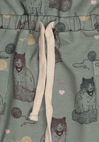 Grüßer Stoff mit einem Muster aus stilisierten Katzen und Wollknäulen. Kordelzug mit cremefarbener Schnur. Weiche Textur, lässige Passform.