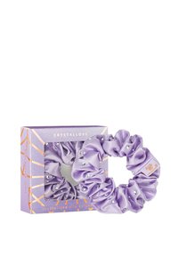 Fioletowy jedwabny kucyk ozdobiony przezroczystymi kryształami, zaprezentowany w pudełku w geometryczny wzór z złotymi akcentami i nazwą marki.