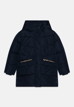 Marineblå pufferjakke med hette, med to gyldne glidelåslommer foran, sydd detaljer og rett passform. Glatt materialtekstur.