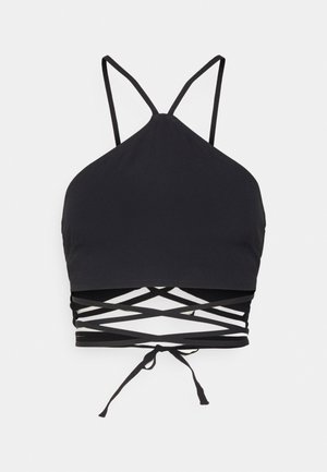 Top corto negro de estilo halter con tirantes finos y detalle de lazo cruzado en la cintura, mostrado sobre un fondo blanco.