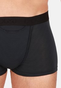 Boxer da uomo a strisce nere con una texture liscia, caratterizzati da un'ampia vita elastica stampata con il nome del marchio. Design aderente.