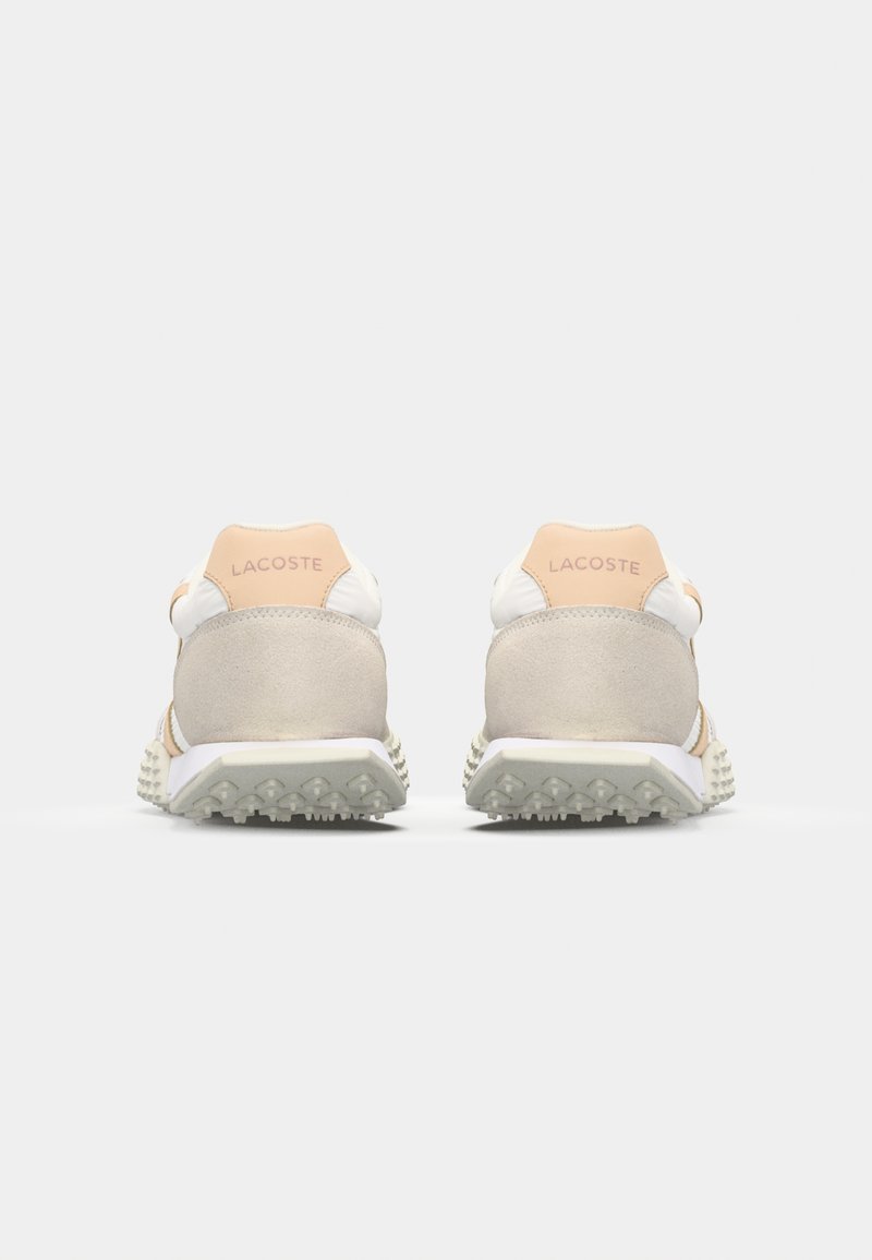 Lacoste Sneakers mit einem Obermaterial aus beigem Wildleder und weißem Textil, mit einem hellen Pfirsich-farbenen Fersenlabel und einer strukturierten weißen Sohle mit Noppen.