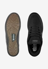 Baskets noires à lacets avec semelle texturée arborant le logo Michelin, présentées en vues de dessus et de dessous sur fond blanc.