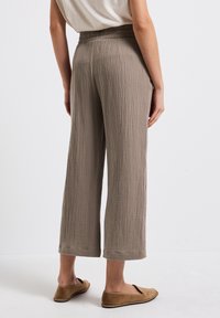 Lichte, taupe-kleurige, wijde broek gemaakt van textuurstof. Elastische tailleband met een ontspannen pasvorm, eindigend net boven de enkel.