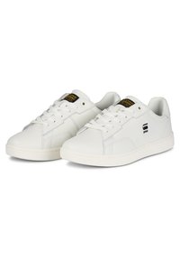 Baskets blanches en cuir lisse avec un design classique à tige basse, dotées de lacets blancs, d'un logo noir sur le côté et d'une semelle rembourrée.