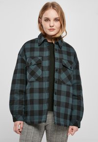 Camicia in flanella a quadri nera e teal, con tasche a patta con bottoni e colletto classico, realizzata in un tessuto morbido e texturizzato.