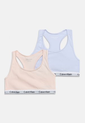 Twee Calvin Klein racerback sportbeha's in pastelroze en lichtblauw met merk elastische banden op een witte achtergrond.