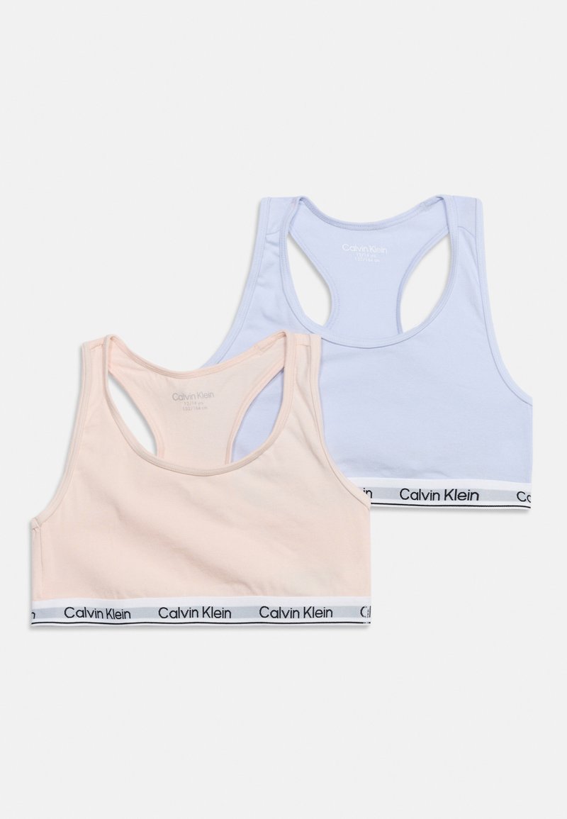 Δύο αθλητικά σουτιέν Calvin Klein με racerback σε παστέλ ροζ και ανοιχτό μπλε χρώμα με λαστιχάκια με λογότυπο σε λευκό φόντο.