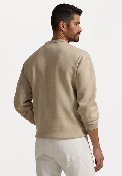 Lys beige hettegenser med rund hals, ribbede mansjetter og en avslappet passform. Tøyet ser mykt ut med en jevn tekstur.