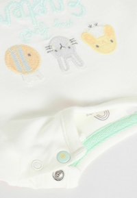 Body de bébé blanc avec des designs d'animaux colorés brodés : poisson, lapin et poussin. Fermeture avec des accents vert menthe et des boutons décoratifs.