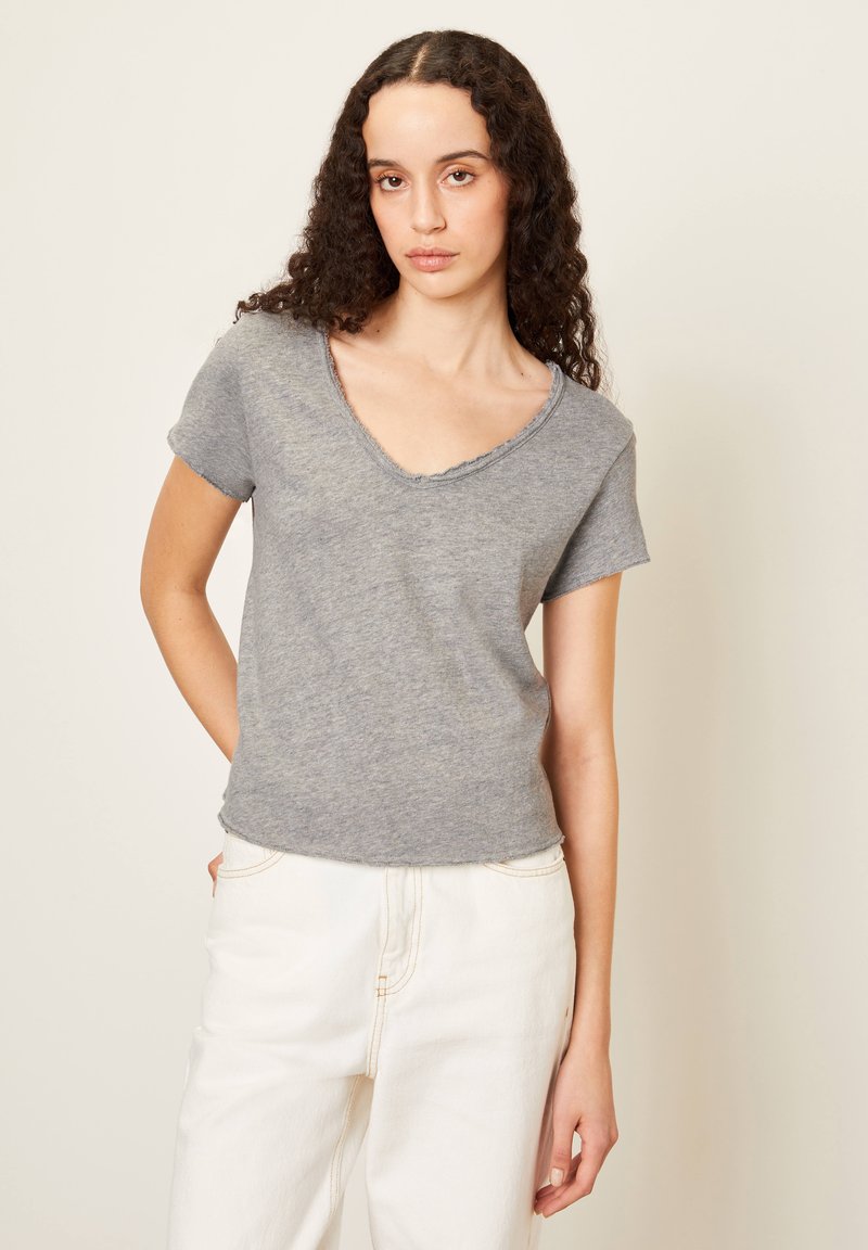 Pilkas trumpas rankovėmis marškinėliai su V formos iškirpte, su šiek tiek išrudytais kraštais ir lengvu medvilnės mišinio audiniu. Derinami su baltais kelnėmis.