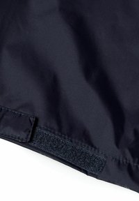 Mörkblått tyg med en slät yta; har en kardborreband längs kanten för fastsättning; minimalistisk design utan mönster.