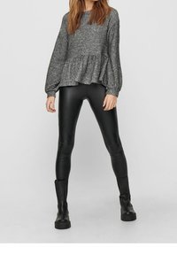 Grau gerippter Peplum-Pullover mit langen Ärmeln, kombiniert mit schwarzen Fake-Leder Skinny-Hosen und mattschwarzen Ankle-Boots.