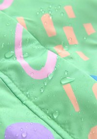 Waterdicht fabric in het groen met abstracte patronen in roze en oranje. Bevat waterdruppels op het oppervlak, wat wijst op de waterdichte kwaliteit.