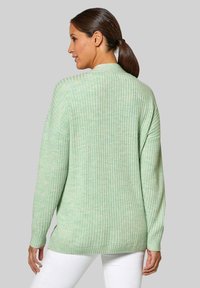 Lichtgroene geribde trui met lange mouwen, hoge hals en een losse fit. Getextureerde stof en zijsplitten aan de onderrand voor extra comfort.