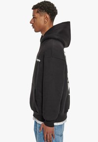 Schwarzer Kapuzenpullover mit Kängurutasche, gerippten Bündchen und Saum. Verfügt über Logodetails auf der Vorderseite und einen einfachen, lässigen Schnitt.