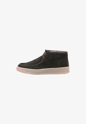 Bottines en suède gris foncé avec des lacets marron contrastants, semelle en caoutchouc clair et coutures blanches le long du bord. Design à bout arrondi.