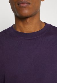 Purple cotton t-shirt with a crew neck collar and short sleeves; smooth texture and even color; no visible patterns or accents.