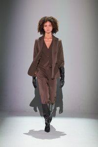 Traje marrón a medida con pantalones de cintura alta, una chaqueta y un chaleco ceñido. Combinado con botas de cuero negras hasta la rodilla y guantes.