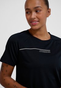 Black athletic T-shirt with short sleeves, featuring a white logo and accent line. Made of textured fabric, it has a round neckline.