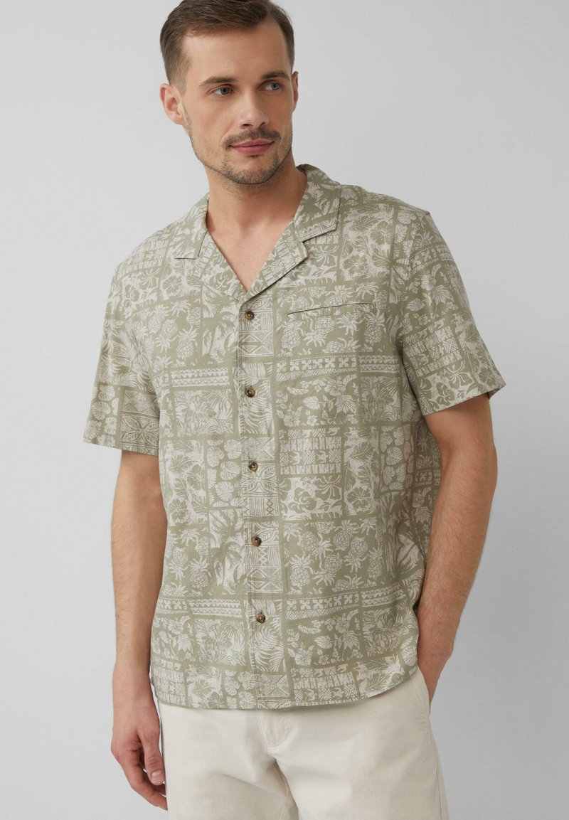 Korte mouwen shirt van lichtgroene stof, met een bloemen- en geometrisch patroon, v-hals en houten knopen.