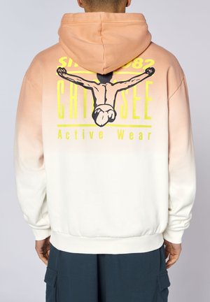 Mann trägt einen Hoodie mit Pfirsich-zu-Weiß-Verlauf, auf der Rückseite mit Grafik eines Tauchers und gelbem Text "Since 1982 CHOOSE Active Wear".