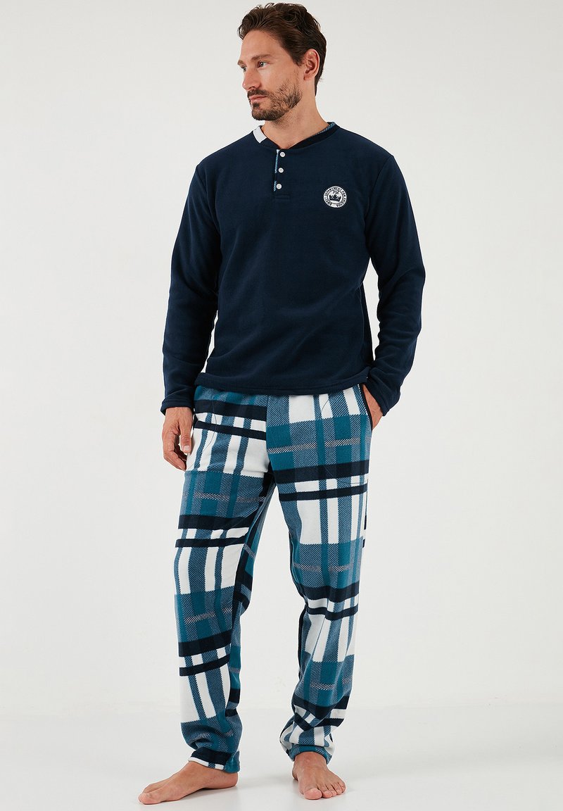 Marineblå fleece langærmet top med tre knapper og logo, parret med blå og hvid ternet flannel-bukser med en blanding af striber.