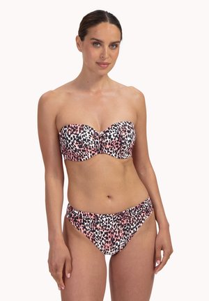 Kobieta w bikini bez ramiączek z różowym, białym i czarnym wzorem w zwierzęcy print, stojąca na tle jednolitego białego tła.