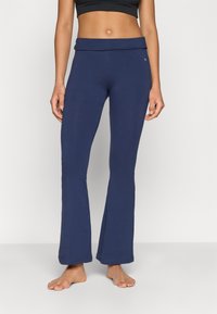 Tmavomodré rozšírené jogové nohavice s mäkkým pásom, vyrobené z elastickej látky. Hladká textúra, bez viditeľných vzorov alebo doplnkov.