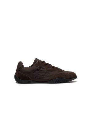 Zapatilla baja de color marrón oscuro con cierre de cordones, panel lateral texturizado y suela de goma negra, mostrada de perfil sobre fondo blanco.